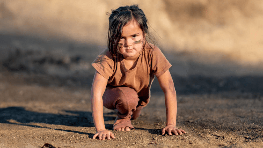 Child wearing brown clothes in a start race position