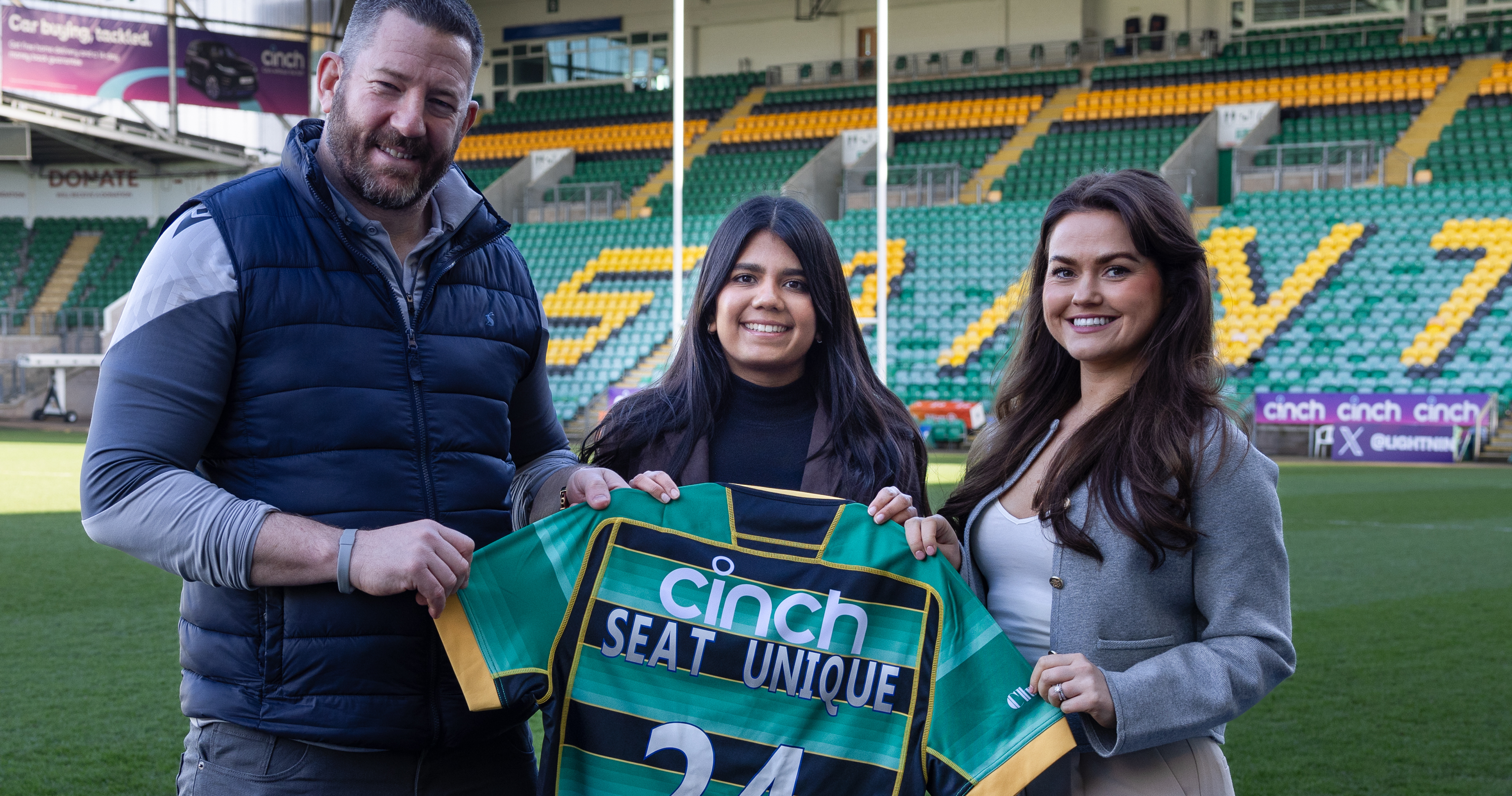 Staff from Northampton Saints and Seat Unique holding shir