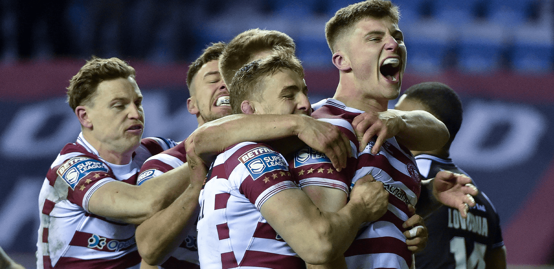 Wigan Warriors players huddle together celebrating score