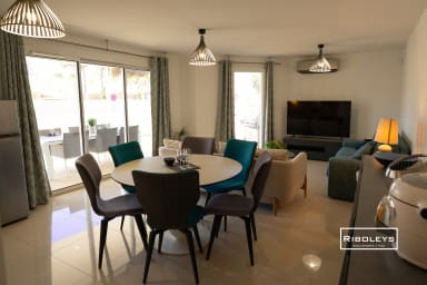 Grande pièce de vie climatisée avec table à manger et cuisine ouverte.