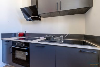 Cuisine équipée avec four, grille pain, machine à café et plaque de cuisson