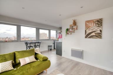 Pièce à vivre avec canapé convertible, coin repas, cuisine et des fenêtres...