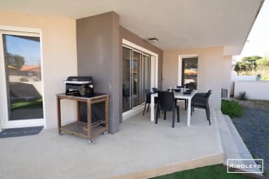 Grande terrasse avec coin repas et barbecue.