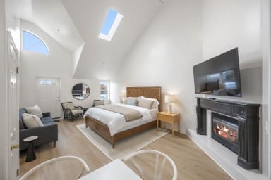 Inviting king bedroom featuring a sofa bed, TV, and cozy fireplace