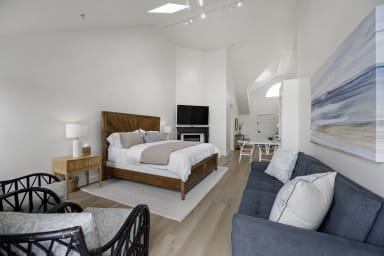 Inviting king bedroom featuring a sofa bed, TV, and cozy fireplace
