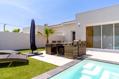 Terrasse avec table, parasol et transats près de la piscine
