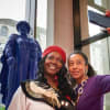 Lara Rose and Corinne Bailey Rae pose for a photo in front of the Geraldine Connor statue at Leeds Beckett University