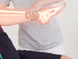 Physiotherapeut bewegt das angewinkelte Bein einer Patientin während einer Krankengymnastik-Behandlung; grafische Darstellung von Knochen und Gelenken verdeutlicht den Bewegungsapparat und die Wirkung der Therapie.
