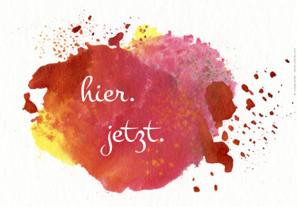 Ein Bild mit einem abstrakten roten, orangefarbenen und gelben Farbklecks auf weißem Hintergrund. In der Mitte des Farbklecks steht in weißer Schrift "hier. jetzt.".