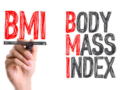 Ein Bild zeigt eine Hand, die mit einem schwarzen Marker das Akronym "BMI" schreibt. Rechts daneben stehen die Wörter "BODY MASS INDEX", wobei die Anfangsbuchstaben "B", "M" und "I" rot markiert sind.