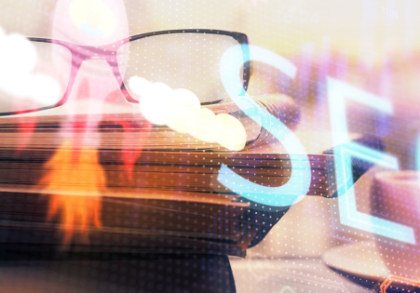 Symbolbild für SEO mit Fokus auf Online-Marketing im Gesundheitswesen: Überlagerte Schrift „SEO“, Bücherstapel mit Brille und Kaffeetasse im Hintergrund, abstrakte Lichteffekte.