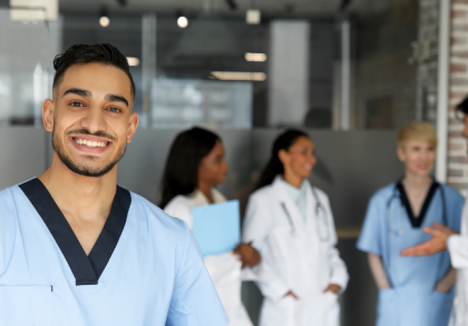 Lächelnder internationaler Gesundheitsfachkraft in Klinik, im Hintergrund multikulturelles Ärzteteam im Gespräch – Symbol für Integration, Fachkräftezuwanderung und Anerkennung im deutschen Gesundheitswesen