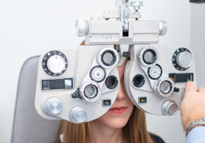 Frau bei augenärztlicher Sehstärkenmessung mit Phoropter während einer professionellen Augenuntersuchung in der Praxis, Arzt stellt die Linsen zur Bestimmung der optimalen Sehkorrektur ein.