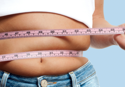 Frau misst ihren Bauchumfang mit einem Maßband um die Taille – Symbolbild für Übergewicht, Gewichtszunahme und mögliche Ursachen wie Ernährung, Bewegungsmangel oder Lebensstil.