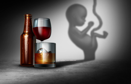 Ein braunes Bierflasche, ein Glas Rotwein und ein Glas Whiskey mit Eiswürfeln stehen auf einem betonartigen Untergrund. Die Flasche und Gläser werfen einen Schatten in Form eines Fötus an die Wand im Hintergrund.