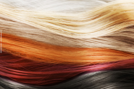 Nahaufnahme von mehreren Schichten von Haaren in verschiedenen Farben, darunter Weiß, Blond, Orange, Rot, Rosa und Schwarz.