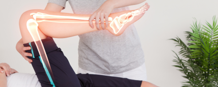 Physiotherapeut bewegt das angewinkelte Bein einer Patientin während einer Krankengymnastik-Behandlung; grafische Darstellung von Knochen und Gelenken verdeutlicht den Bewegungsapparat und die Wirkung der Therapie.
