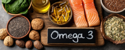 Omega-3-reiche Lebensmittel wie Lachs, Fischölkapseln, Chiasamen, Nüsse und Leinöl auf Holzuntergrund – Darstellung gesunder Ernährung zur Unterstützung der Herzgesundheit und Versorgung mit Omega-3-Fettsäuren.