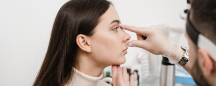 Arzt untersucht die Nase einer Patientin im Profil und prüft Nasenform und Gesichtsproportionen vor einer möglichen Nasenoperation.