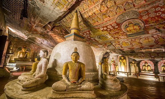 Im Kreis angeordnete Buddha-Statuen und verzierte Gewölbe im Goldenen Höhlentempel von Dambulla in Sri Lanka