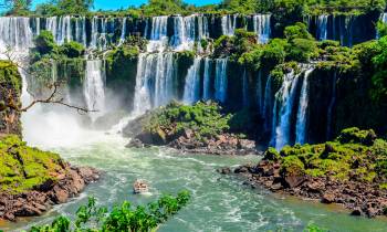 a large waterfall over some water with Kravica in the background