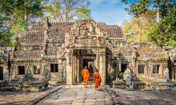 a person standing in front of a stone building with Angkor Wat in the background