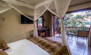 a bedroom with a bed and a chair in a room