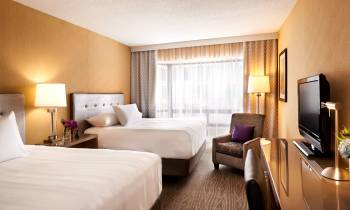 a bedroom with a bed and desk in a hotel room