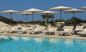 a group of lawn chairs sitting next to a pool of water