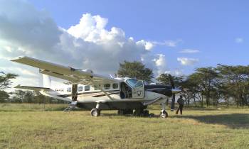 a plane sitting on top of a grass covered field with Castle Air Museum in the background