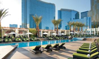 a group of people sitting on a bench in a park with Mandarin Oriental, Las Vegas in the background
