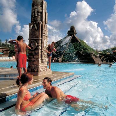 a group of people swimming in a pool of water with Disney's Coronado Springs Resort in the background