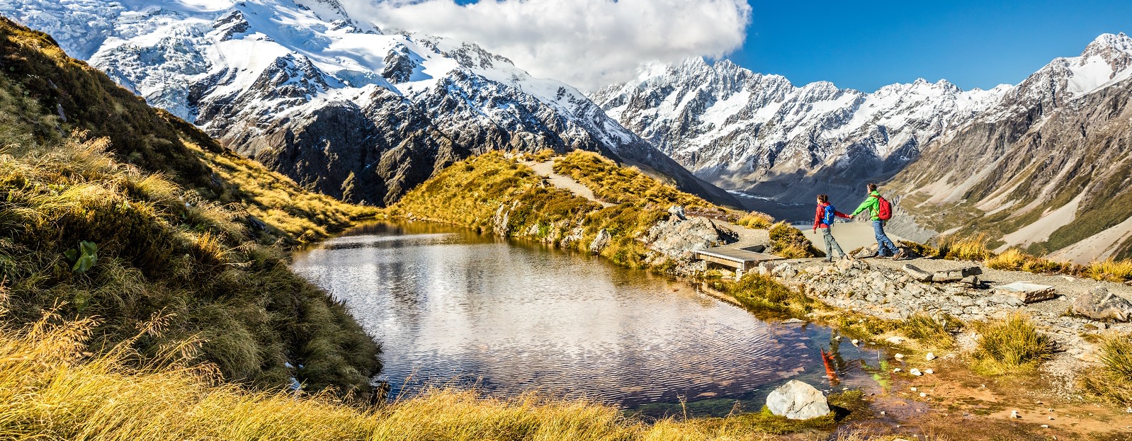 Hiking travel nature hikers in New Zealand. Couple people walking on Sealy Tarns hike trail route with Mount Cook landscape, famous tourist attraction Hiking travel nature hikers in New Zealand. Couple people walking on Sealy Tarns hike trail route with Mount Cook landscape, famous tourist attraction - New Zealand travel