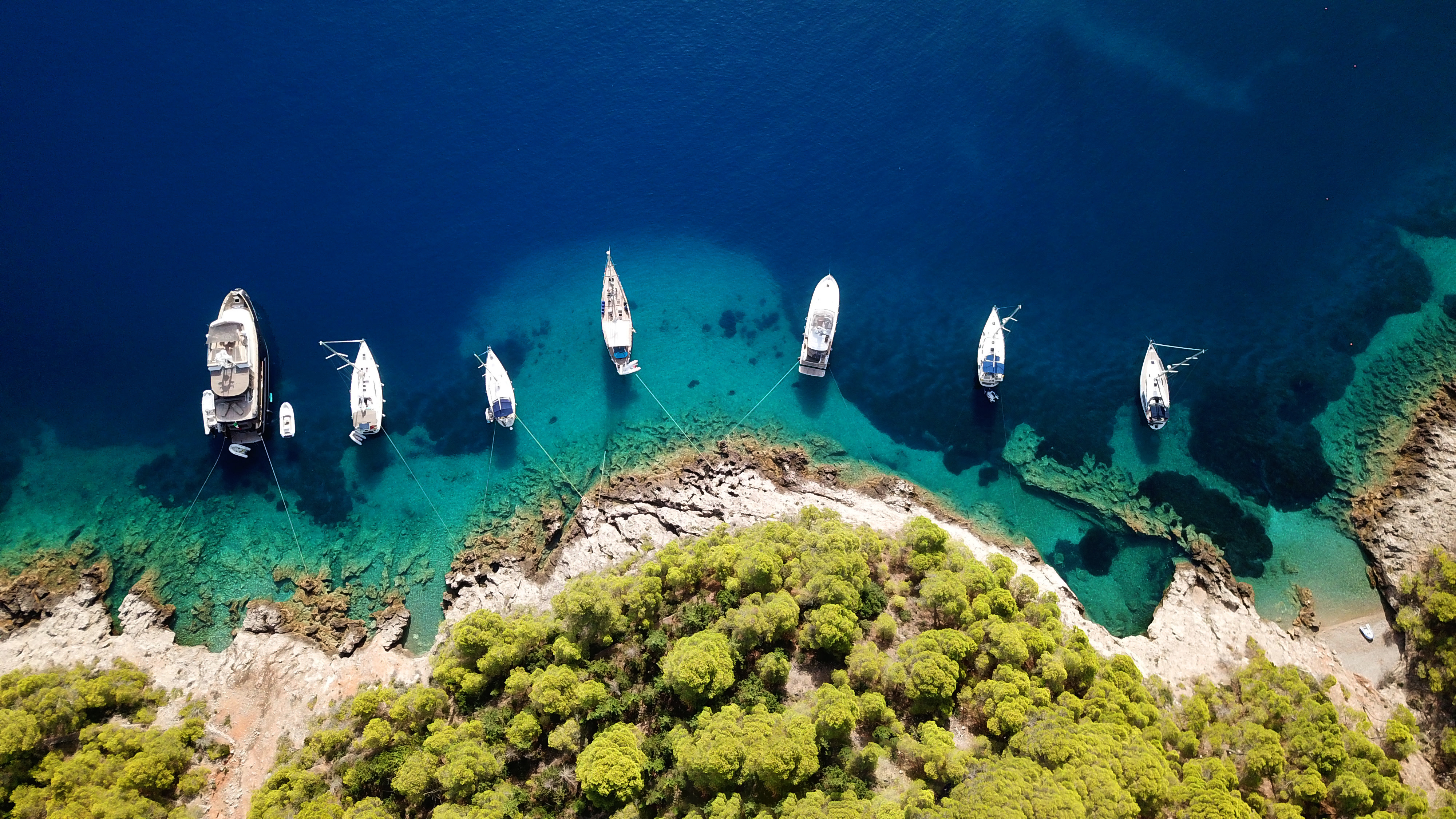 Aerial photo of luxury sail boat docked in tropical caribbean rocky turquoise color seascape best time to visit Greece