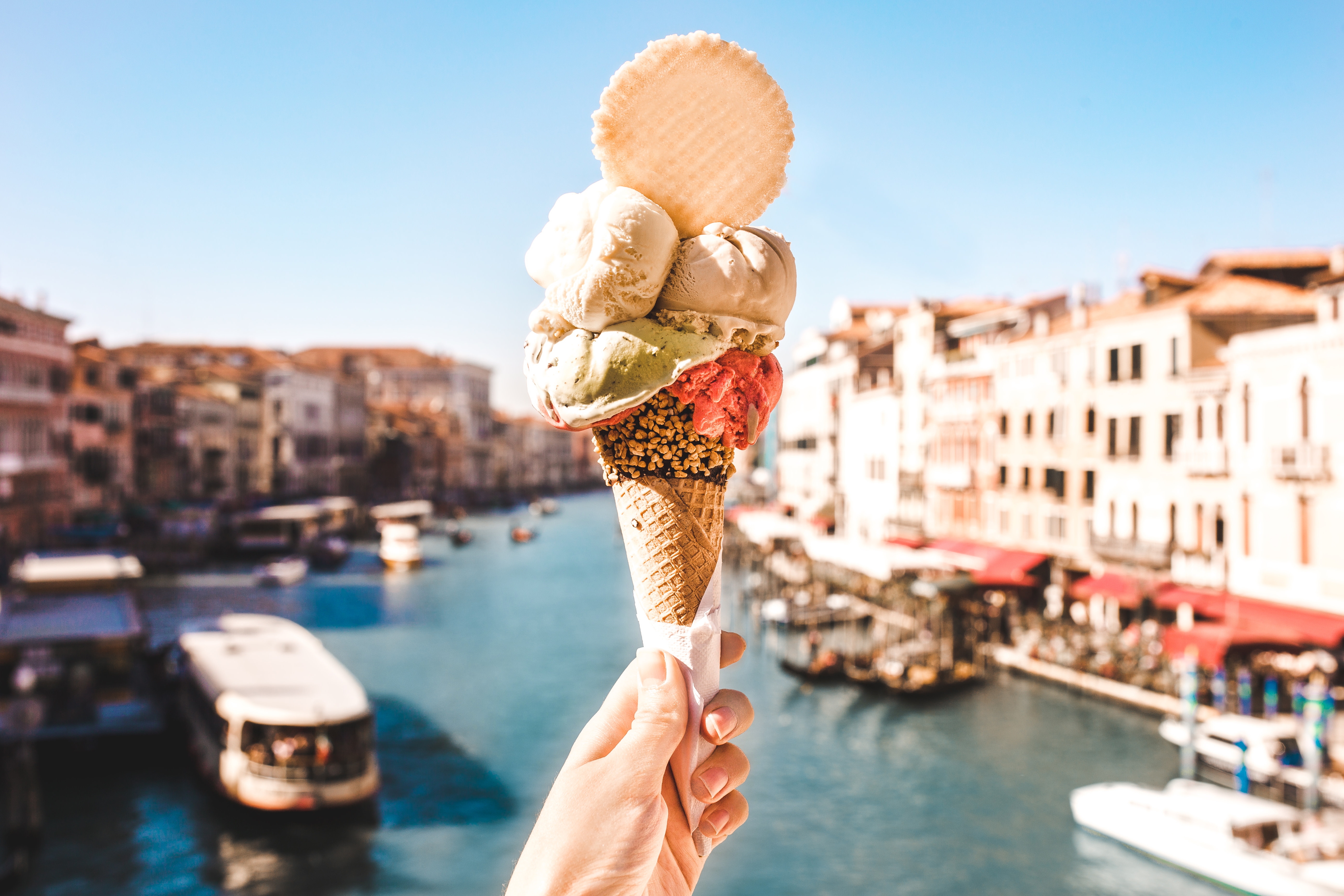 Enchanting Travels Delicious icecream in beautiful Venezia, Italy in front of a canal and historic buildings