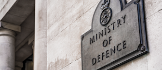 Plaque on a stone wall reads "Ministry of Defence" with a crown emblem above. Columns are visible in the background.