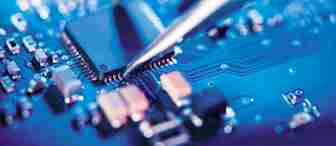 Close-up of tweezers placing a microchip onto a blue printed circuit board (PCB), showcasing electronic components and intricate conductive pathways, with a blurred background creating a focused detail on the microchip and its precise positioning.