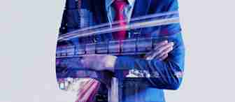 Double exposure of a man in a suit with arms crossed. His silhouette overlays a dynamic cityscape featuring buildings and light trails, symbolizing urban development and business. The man wears a blue suit and a red tie, implying professionalism and confidence.