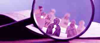 A large magnifying glass focuses on paper cut-outs of human figures, each decorated with various letters and text passages. The background shows more paper figures out of focus, positioned on an open book, creating a scene with text and paper characters.