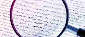 A magnifying glass lying on top of a document, enlarging the text beneath it. The document contains formal legal language and is printed in black font on white paper. The magnified text mentions liability and agreements.