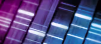 A vibrant, abstract image featuring vertical bands of light in varying shades of pink, purple, and blue, resembling a sound equalizer or frequency spectrum. The bands are irregularly spaced and somewhat blurred, creating a dynamic and futuristic effect.