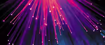 An abstract image featuring numerous streaks of vibrant pink, purple, and blue light radiating downward against a dark background. The lights create a dynamic, almost fiber-optic effect, with glowing orbs resembling bokeh effects scattered at the bottom.