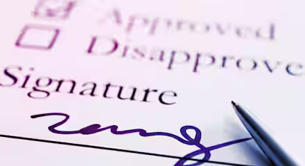 Close-up image of a form featuring checkboxes labeled "Approved" (checked) and "Disapproved" (unchecked), with the word "Signature" below them. A cursive signature is written on the signature line, and a pen is placed near the signature.