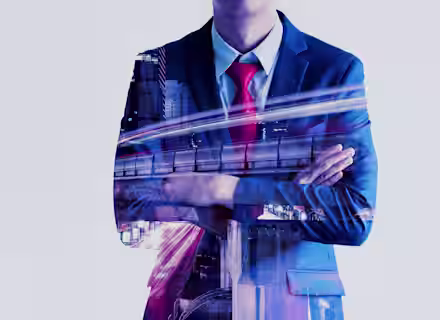 Double exposure of a man in a suit with arms crossed. His silhouette overlays a dynamic cityscape featuring buildings and light trails, symbolizing urban development and business. The man wears a blue suit and a red tie, implying professionalism and confidence.