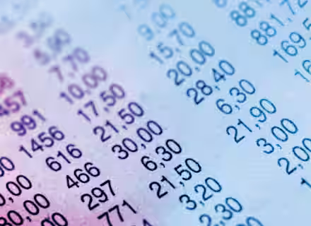 Close-up of a printed sheet displaying rows of numerical data in blue ink. The numbers are organized in columns and rows, some of which include values such as 297, 6.30, and 15.00. The sheet has a slight gradient with shades of blue and pink.