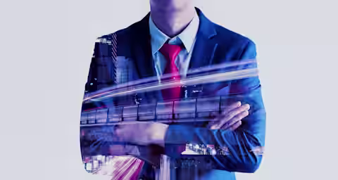 Double exposure of a man in a suit with arms crossed. His silhouette overlays a dynamic cityscape featuring buildings and light trails, symbolizing urban development and business. The man wears a blue suit and a red tie, implying professionalism and confidence.