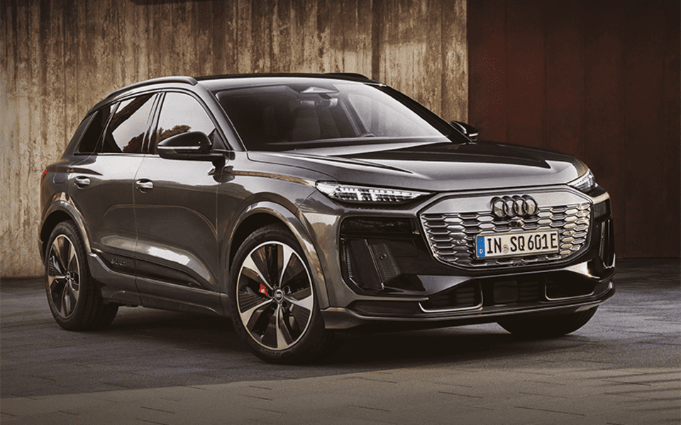 Audi Q6 fra Frydenbø Bil parkert foran trebygg