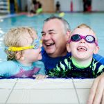 man swimming with two children