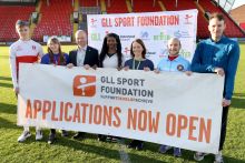 Photo of a group of athletes at a sports stadium holding a banner for the GLL Sport Foundation 