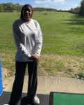 Female standing in a driving range, holding a golf club Female standing in a driving range, holding a golf club